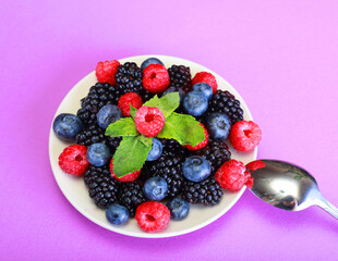 Various berries in a white plate. Blueberries, blackberries and raspberries are delicious diet berries.