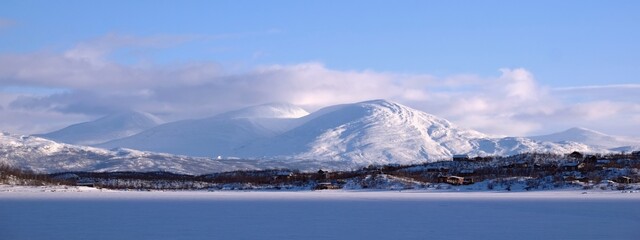 Beautiful scenery of snowy mountains in clouds. View from Lake Torneträsk (Tornestrask) around...