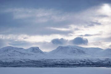 Winter mountain panorama with Lapporten (Lapponian Gate) or Tjuonavagge, U-shaped valley around Abisko National Park in Lapland, Sweden, Arctic Circle. View from lake Torneträsk (Tornestrask)