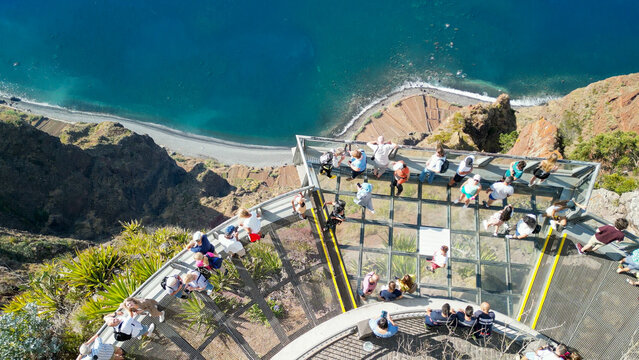 Tourists enjoy the viewpoint at Cabo Girao, along the Madeira coastline, Portugal. Aerial view from drone