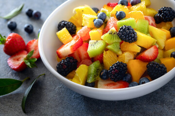 Bowl of healthy fresh summer mixed fruit salad close-up. Plate delicious and wholesome food with copy space