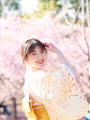 Portrait of beautiful young Chinese girl in Japanese kimono posing with blossom cherry flowers...