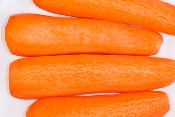 Fresh peeled carrots on white dish, top view close-up