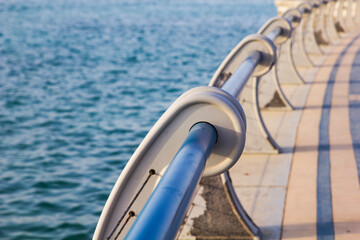 Metal railing next to the beach ocean on a sunny day