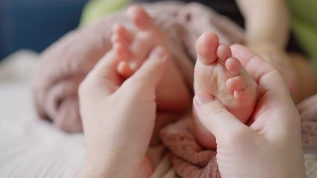 Mom doctor gives a foot massage to her baby. happy family kid baby concept. Children massage: care and care of the doctor mother. Foot massage baby health: doctor mom help. dream baby foot massage