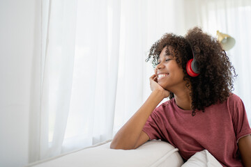 Fototapeta na wymiar Young African woman sitting and listening the music. Portrait of happy woman listening music with earphones while singing song.