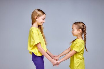 elder sister entertains her little one, two smiling awesome kids have fun at studio. making circle, holding hands, singing songs, dancing, isolated white background