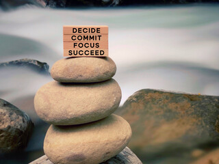 Inspirational and motivational words of decide commit focus succeed on wooden blocks with vintage background.