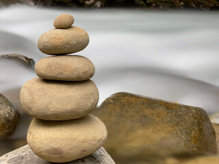Stack of balanced stones with long exposure of water river background. 