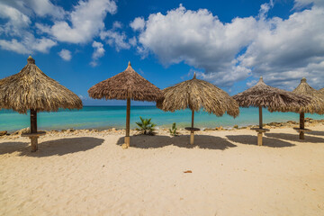 Gorgeous view of sandy Eagle beach turquoise water of Atlantic ocean with sun parasols. Aruba. 