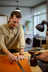 young hardworking tailor concentrated on sewing belt. close up shot, business. guy creates handmade project indoors