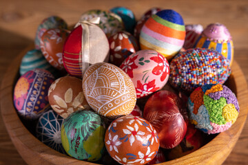 Fototapeta na wymiar A wooden bowl with closely arranged Easter eggs stands on a background of boards.