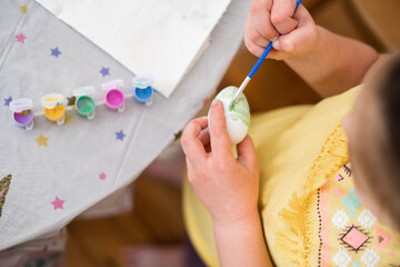 Child girl of preschool age painting Easter eggs at home kitchen. Easter spring traditions. Slow motion