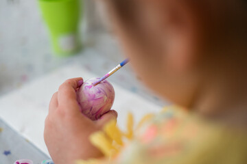 Child girl of preschool age painting Easter eggs at home kitchen. Easter spring traditions. Slow motion