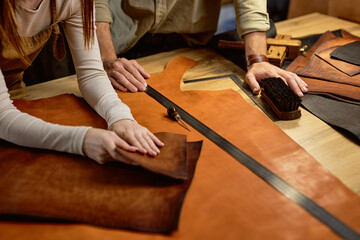 Working process in the leather workshop. people's hands holding crafting material. close up cropped shot