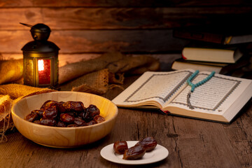 Many Date Palms are on bowls, plates, a cup of water, and Quran, an Islami-style lamp on the wooden tables, to wait for the time of Iftar, with the concept of fruits from Muslims around the world.