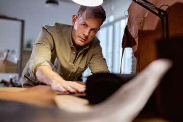 handsome tailor with hands, palms on the material looks at camera, close up cropped portrait.