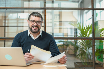 Happy adult man holding documents and looking at camera