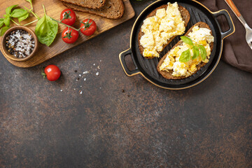Scrambled eggs on whole grain bread. Homemade breakfast or brunch meal - scrambled eggs. View from above. Copy space.