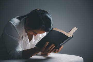 woman kneeling and praying in modern house at sunset time. Female catholic prayer worship to God...