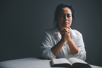 woman kneeling and praying in modern house at sunset time. Female catholic prayer worship to God...