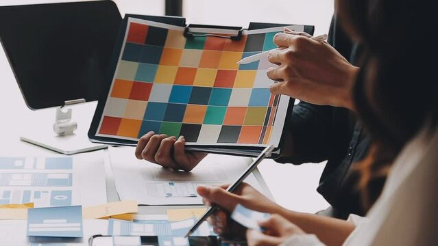 Close up ux developer and ui designer brainstorming about mobile app interface wireframe design on table with customer breif and color code at modern office.Creative digital development agency