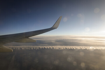 Obraz premium Commercial airlines aeroplane above the clouds very early in the morning with light flares.