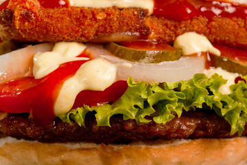 Burger with meat and fried yellow cheese with onions tomatoes cucumber lettuce and sauces. Abstract fast food photo.