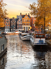 Amsterdam Netherlands, Holland. Dancing houses over river Amstel landmark in old european city fall landscape. House boats on the water. Autumn evening street - obrazy, fototapety, plakaty