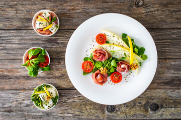 Tasty salad - prosciutto crudo, melon and fresh vegetables on wooden table
