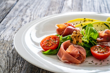 Tasty salad - prosciutto crudo, melon and fresh vegetables on wooden table
