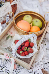 A close-up photo of the fruit table decoration. Strawberries in a basket on a tray on the background of a vase with oranges