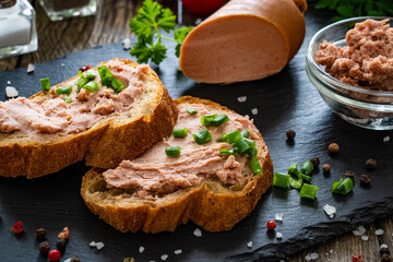 Tasty sandwiches with liverwurst and chive on wooden table
