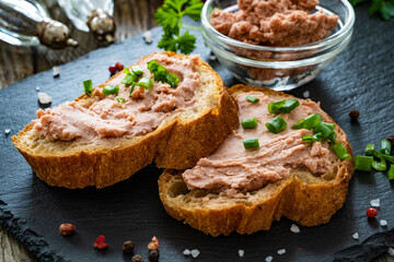 Tasty sandwiches with liverwurst and chive on wooden table
