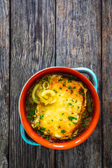 Onion soup with roasted bread with cheese on wooden table
