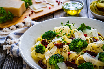 Pasta with broccoli, parmesan and sun dried tomatoes on wooden table
