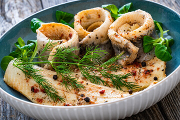 Marinated herring fillets with dill on wooden table
