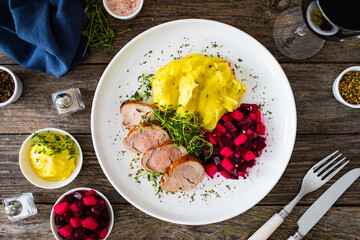 Fried pork loin with potato puree and vegetables on wooden table
