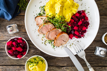 Fried pork loin with potato puree and vegetables on wooden table
