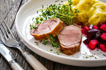 Fried pork loin with potato puree and vegetables on wooden table
