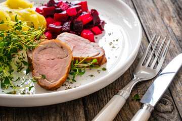 Fried pork loin with potato puree and vegetables on wooden table
