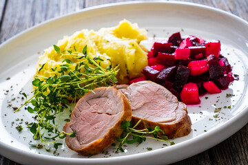 Fried pork loin with potato puree and vegetables on wooden table
