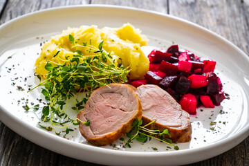 Fried pork loin with potato puree and vegetables on wooden table
