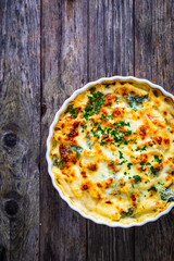 Noodle casserole with roast pork loin, mozzarella cheese, bechamel sauce and spinach on wooden table
