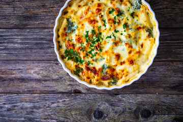 Noodle casserole with roast pork loin, mozzarella cheese, bechamel sauce and spinach on wooden table
