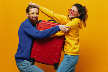 Obraz premium Woman and man smiling, suitcases in hand with yellow and red suitcase smiling merrily and crooked, yellow background, going on a trip, family vacation trip, newlyweds.
