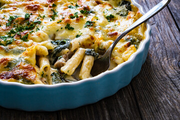 Noodle casserole with roast pork loin, mozzarella cheese, bechamel sauce and spinach on wooden table
