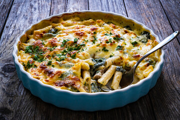Noodle casserole with roast pork loin, mozzarella cheese, bechamel sauce and spinach on wooden...