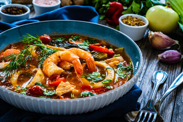 Seafood and fish soup on wooden table
