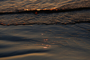 Small dark ocean waves up close in sunset 